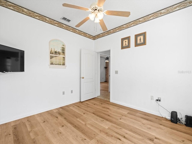 empty room with a ceiling fan, wood finished floors, visible vents, and baseboards