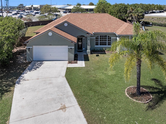 ranch-style house featuring a front yard, fence, an attached garage, stucco siding, and concrete driveway