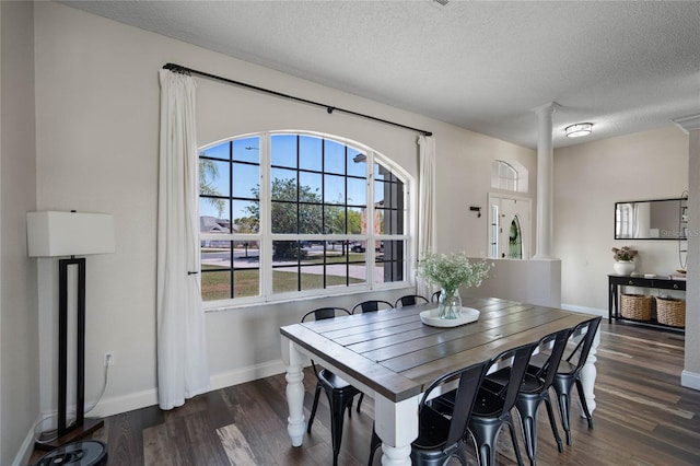 dining room with baseboards, a textured ceiling, dark wood finished floors, and ornate columns