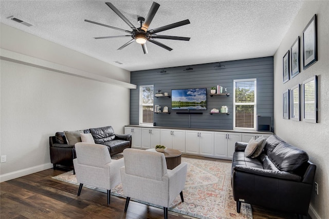 living area featuring baseboards, wood finished floors, visible vents, and a textured ceiling