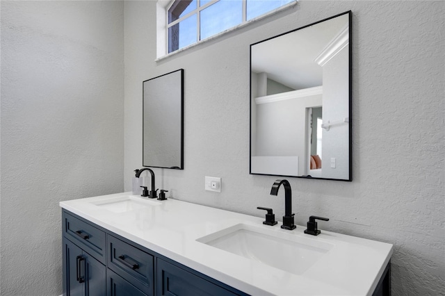 bathroom with double vanity, a textured wall, and a sink