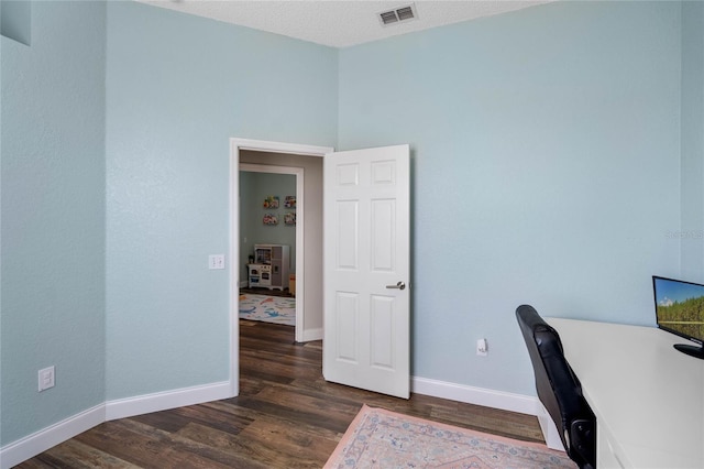 unfurnished office featuring visible vents, baseboards, and dark wood-style flooring