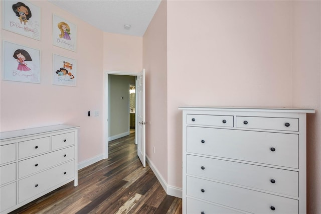 corridor featuring dark wood finished floors, baseboards, and a textured ceiling