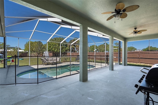 view of pool with a patio, a fenced backyard, glass enclosure, a fenced in pool, and ceiling fan