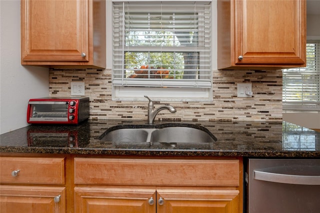 kitchen with a healthy amount of sunlight, a toaster, a sink, decorative backsplash, and stainless steel dishwasher