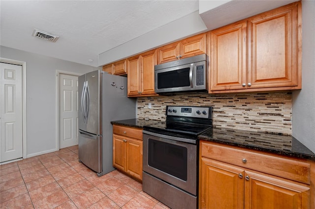 kitchen featuring dark stone countertops, backsplash, visible vents, and appliances with stainless steel finishes