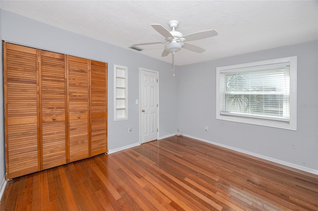 unfurnished bedroom featuring baseboards, visible vents, a closet, wood-type flooring, and a textured ceiling