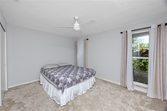 bedroom featuring baseboards, light carpet, a closet, a textured ceiling, and a ceiling fan