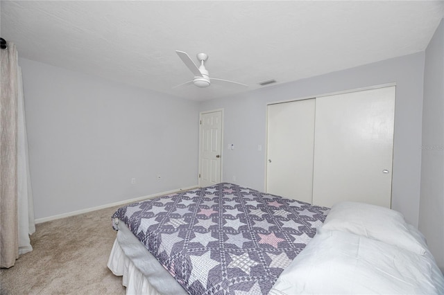 bedroom featuring visible vents, a closet, baseboards, light colored carpet, and ceiling fan