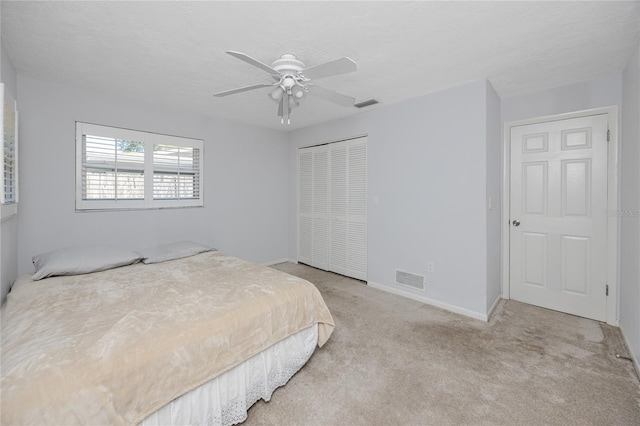 carpeted bedroom with a closet, visible vents, a textured ceiling, and baseboards