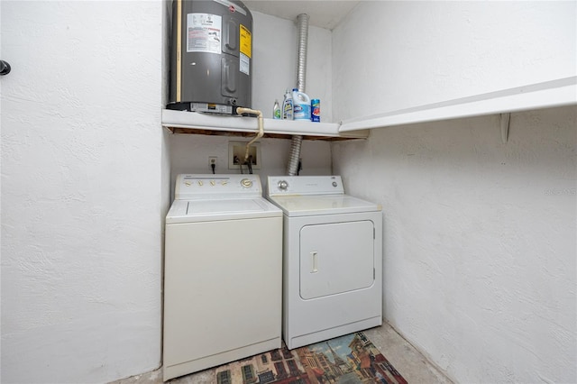 washroom with washing machine and clothes dryer, laundry area, water heater, and a textured wall