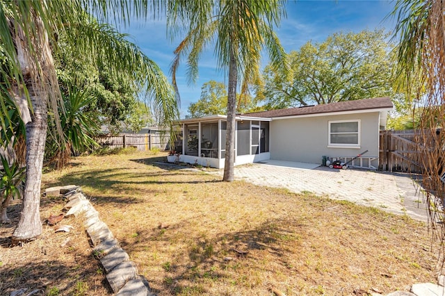 back of house with a fenced backyard, a lawn, a sunroom, and stucco siding