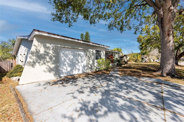 view of property exterior with stucco siding, an attached garage, and driveway