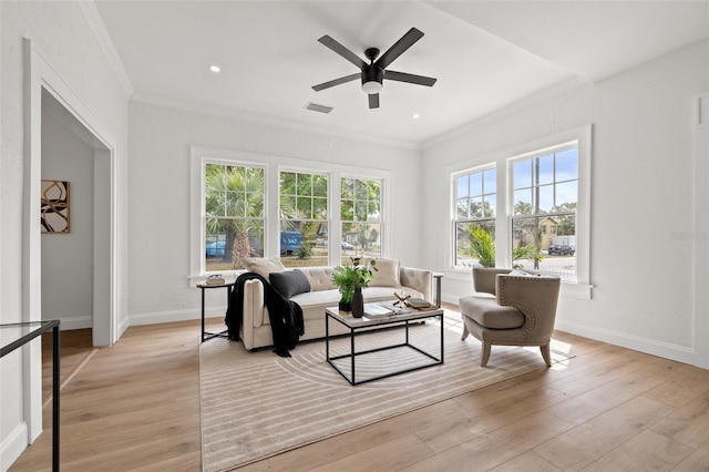 living area with visible vents, baseboards, light wood-style flooring, and ornamental molding