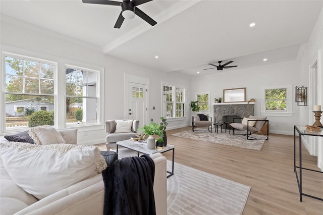 living area featuring baseboards, light wood finished floors, recessed lighting, a stone fireplace, and crown molding