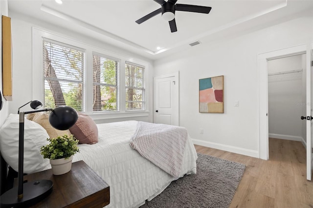 bedroom with baseboards, visible vents, recessed lighting, a raised ceiling, and light wood-type flooring