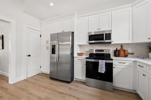 kitchen featuring tasteful backsplash, light countertops, light wood-style flooring, appliances with stainless steel finishes, and white cabinetry