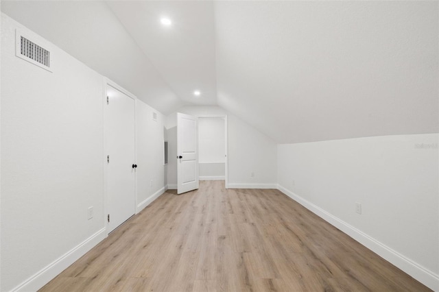 additional living space featuring lofted ceiling, light wood-style floors, visible vents, and baseboards