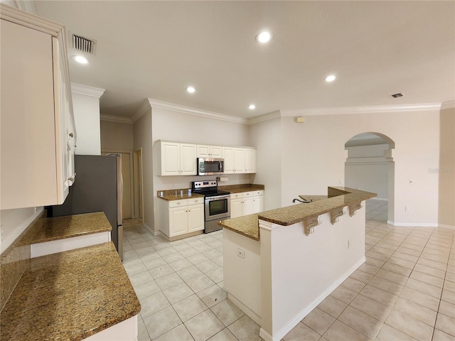 kitchen with light tile patterned floors, recessed lighting, appliances with stainless steel finishes, a kitchen breakfast bar, and white cabinetry