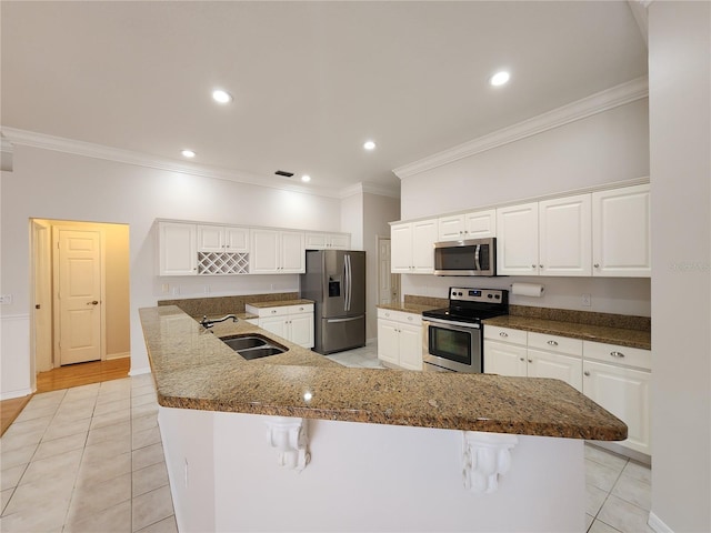 kitchen featuring ornamental molding, a kitchen breakfast bar, stainless steel appliances, and a sink