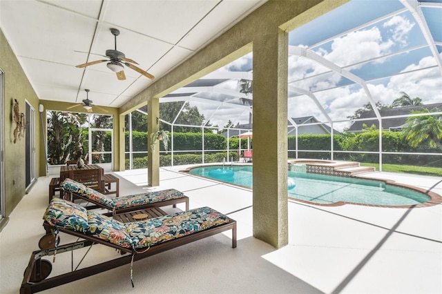 view of swimming pool featuring glass enclosure, a pool with connected hot tub, a ceiling fan, and a patio area