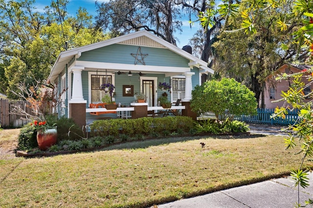 rear view of house featuring a porch, a yard, and fence