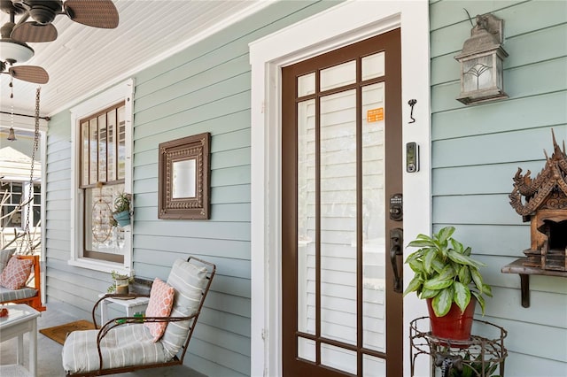 view of exterior entry featuring a porch and a ceiling fan