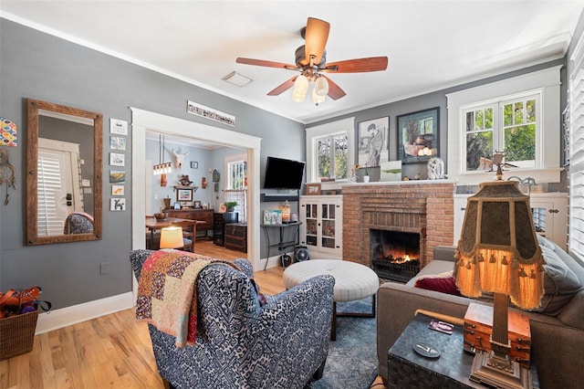 living area with visible vents, a healthy amount of sunlight, a fireplace, and light wood-type flooring