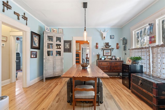 dining room with crown molding, light wood-type flooring, and baseboards