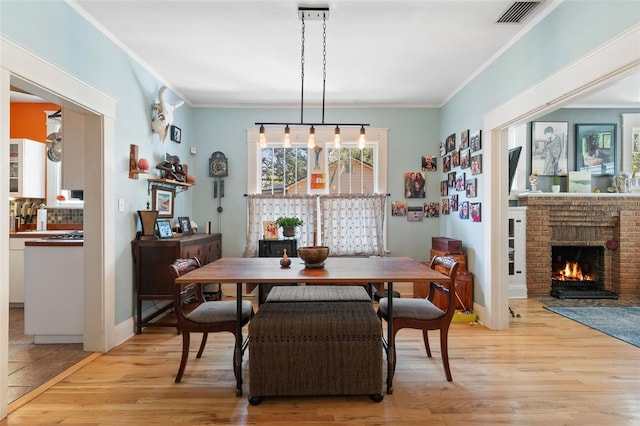 dining room with light wood-type flooring, visible vents, and ornamental molding