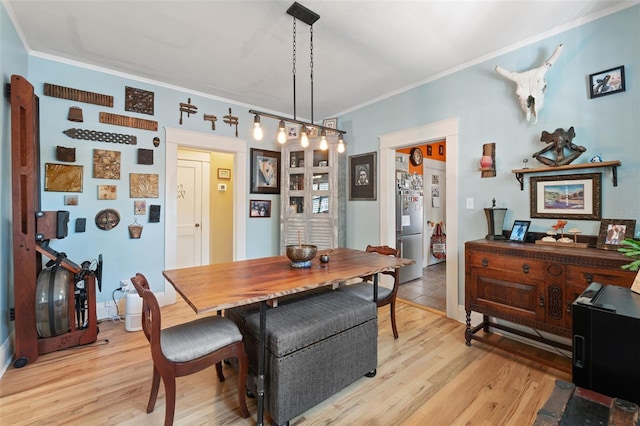 dining space featuring light wood-style floors and crown molding