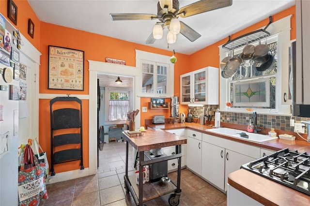 kitchen with backsplash, white cabinetry, a ceiling fan, and a sink