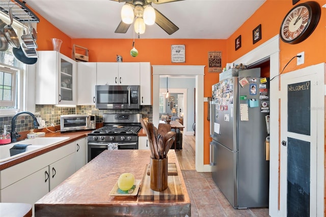 kitchen featuring a sink, decorative backsplash, appliances with stainless steel finishes, and white cabinetry