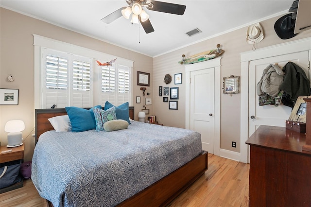 bedroom featuring visible vents, light wood-style flooring, ceiling fan, and ornamental molding