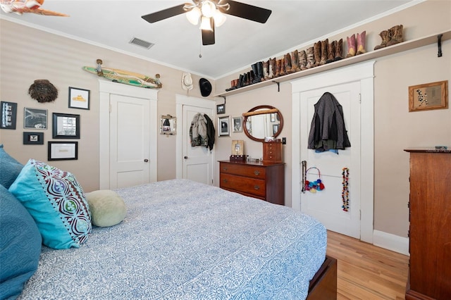 bedroom with visible vents, light wood-style flooring, crown molding, and ceiling fan