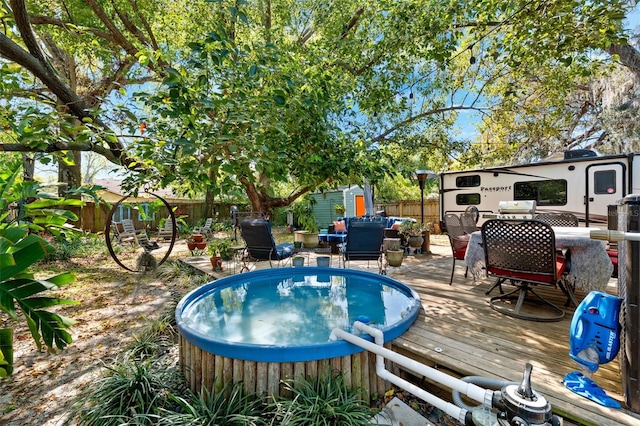 view of swimming pool featuring an outbuilding, a jacuzzi, a wooden deck, and a fenced backyard