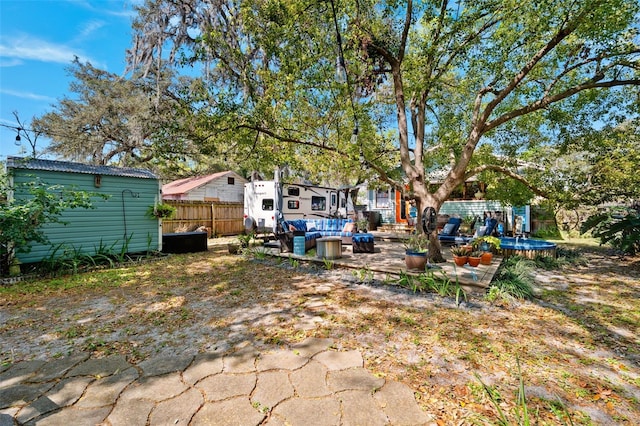 view of yard featuring a storage unit, an outbuilding, an outdoor living space, fence, and a patio area