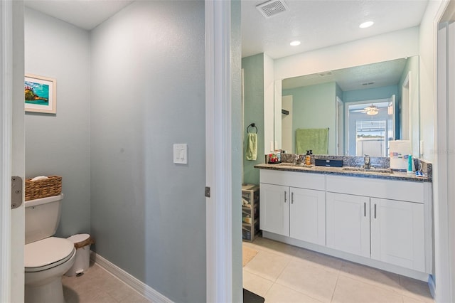 bathroom with vanity, visible vents, baseboards, tile patterned flooring, and toilet