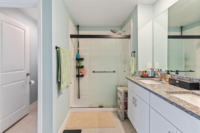 bathroom featuring tile patterned floors, a stall shower, double vanity, and a sink