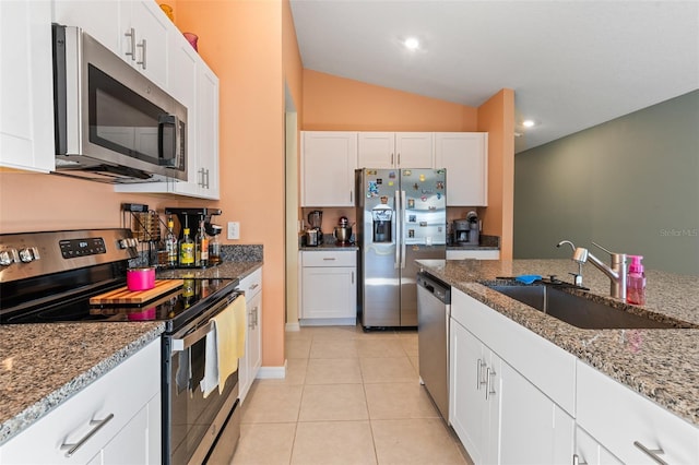 kitchen featuring light stone countertops, light tile patterned floors, appliances with stainless steel finishes, white cabinets, and a sink