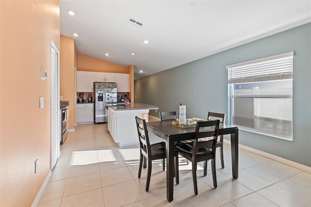 dining space featuring light tile patterned floors, visible vents, baseboards, and vaulted ceiling