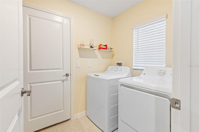 clothes washing area with laundry area, light tile patterned flooring, baseboards, and washer and clothes dryer