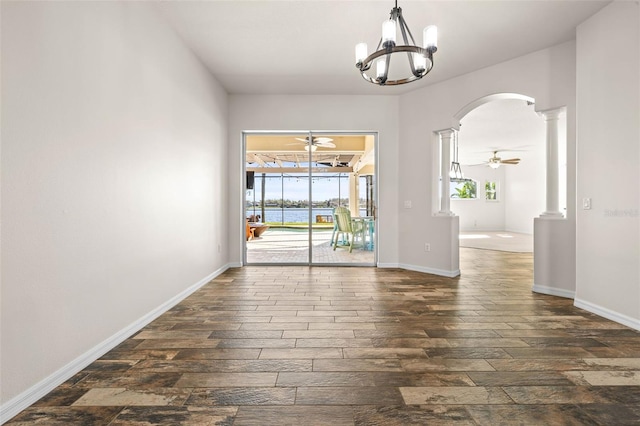 spare room with arched walkways, dark wood-type flooring, a ceiling fan, and a sunroom