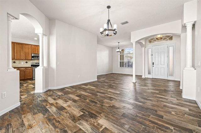 foyer entrance with a notable chandelier, visible vents, dark wood finished floors, and decorative columns