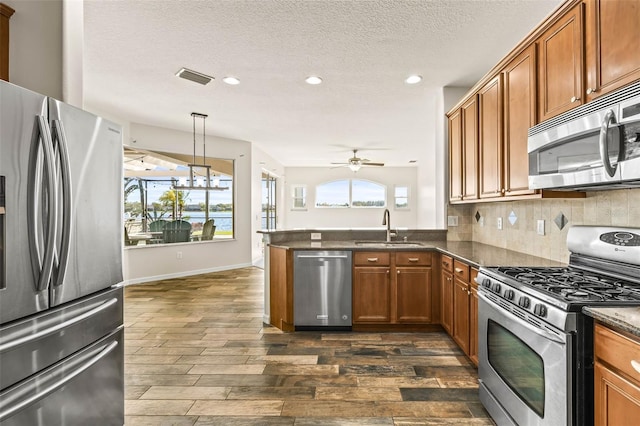 kitchen featuring a sink, brown cabinetry, visible vents, and stainless steel appliances