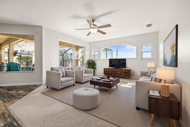 living room featuring baseboards, visible vents, and ceiling fan