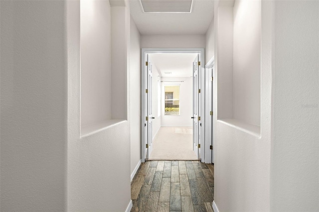 corridor with visible vents, baseboards, and wood finished floors