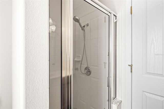 full bathroom featuring a shower stall and a textured wall