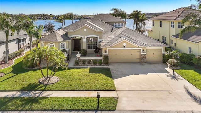 view of front of home featuring a front lawn, a water view, concrete driveway, stucco siding, and a garage