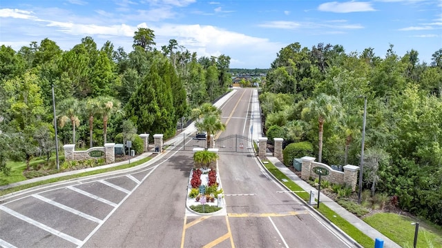 view of street featuring a gated entry, sidewalks, curbs, and a gate